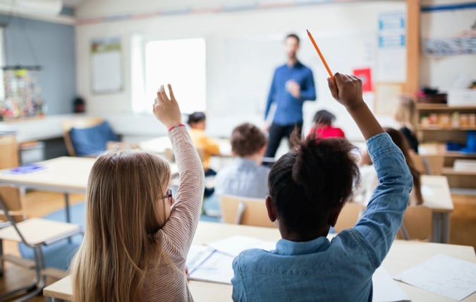 Elever räcker upp handen i ett klassrum