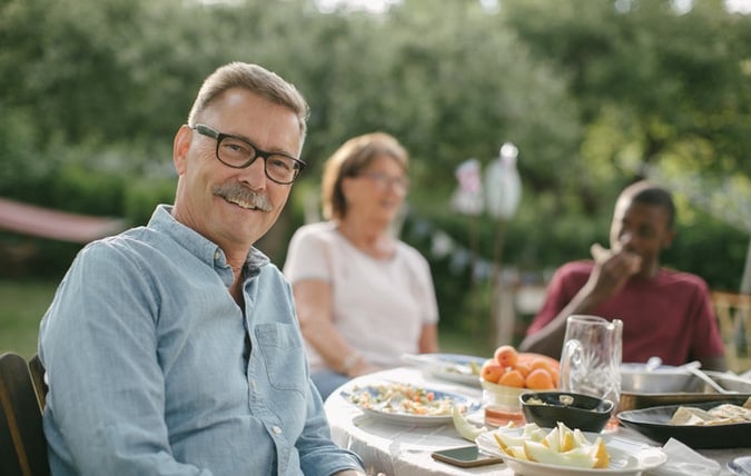 Man vid matbord ler mot kameran 