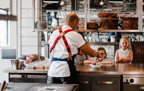 Manlig kock och barn som lagar mat på sin restaurang