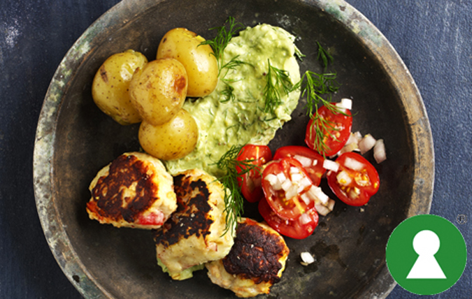 Tallrik med fiskedeller, avokadoröra, tomatsallad och kokt potatis.