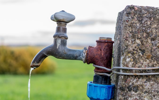 Gammal kran med dricksvatten utomhus monterad på ett betongfundament