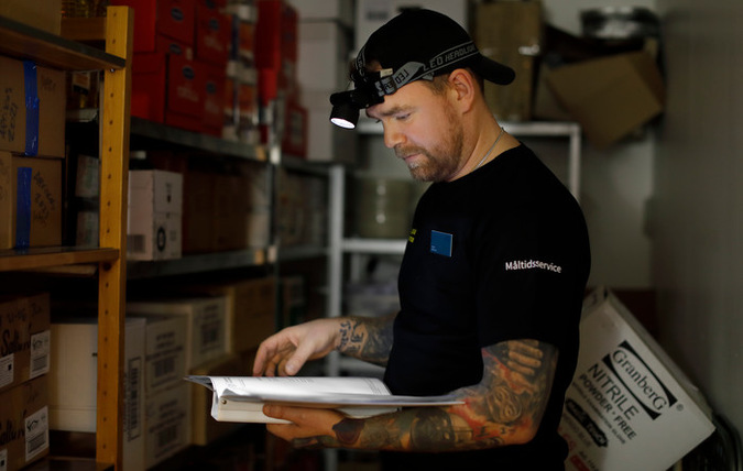 Man läser i krispärm med hjälp av pannlampa i nedsläckt rum.