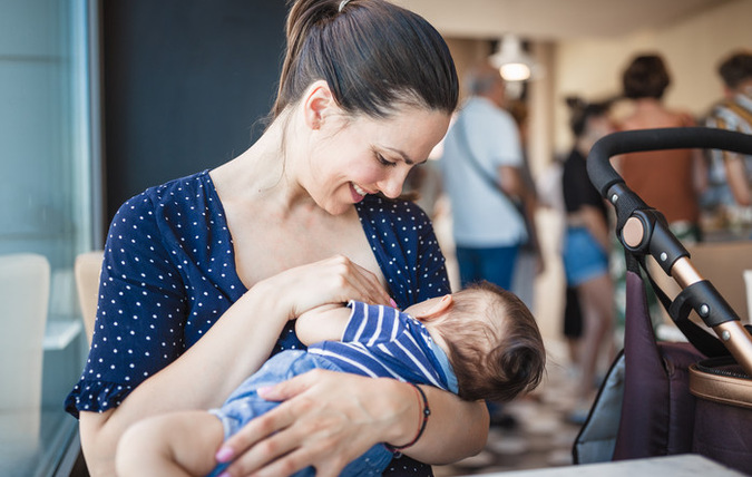 En kvinna som ammar ett spädbarn på ett kafé